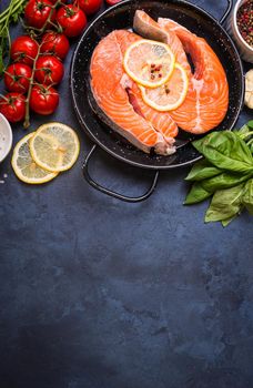 Raw fresh fish with vegetables ready to cook. Raw salmon steak with lemon and spices in a pan. Ingredients for cooking on a concrete background. Space for text. Diet and healthy food. Fish background