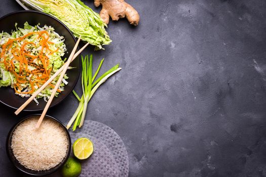 Ingredients for cooking vietnamese dinner: rice paper, rice, napa cabbage, ginger, green onion, salad. Asian cooking ingredients. Top view. Making vietnamese vegetable spring rolls. Space for text