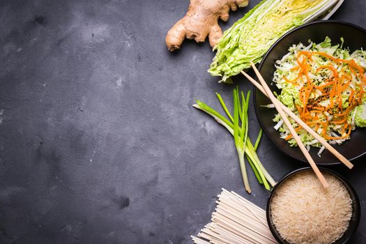 Ingredients for making chinese dinner: wheat noodles, rice, napa cabbage, ginger, green onion. Asian cooking ingredients. Top view. Preparing healthy asian meal with vegetable salad. Space for text