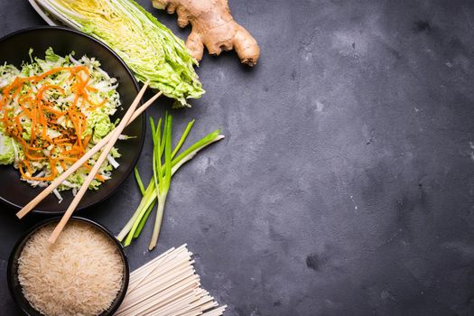 Ingredients for making chinese dinner: wheat noodles, rice, napa cabbage, ginger, green onion. Asian cooking ingredients. Top view. Preparing healthy asian meal with vegetable salad. Space for text