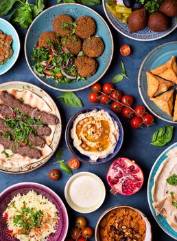 Middle eastern or arabic dishes and assorted meze, concrete rustic background. Meat kebab, falafel, baba ghanoush, muhammara, hummus, sambusak, rice, tahini, kibbeh, pita. Halal food. Lebanese cuisine