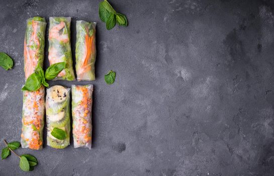 Fresh assorted spring rolls set background. Handmade asian/Chinese spring rolls. Rustic concrete background. Spring rolls with shrimps, vegetables, fruits. Space for text. Top view. Healthy asian food