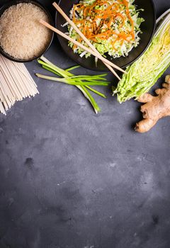 Ingredients for making chinese dinner: wheat noodles, rice, napa cabbage, ginger, green onion. Asian cooking ingredients. Top view. Preparing healthy asian meal with vegetable salad. Space for text