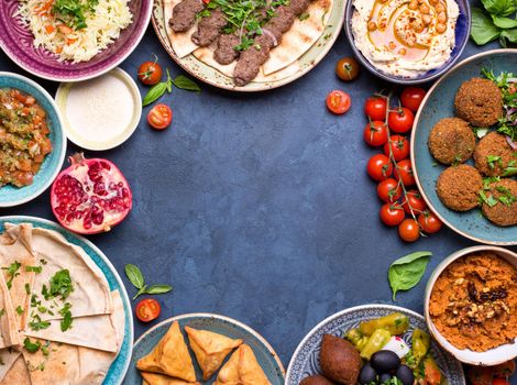 Middle eastern or arabic dishes and assorted meze on concrete rustic background. Meat kebab, falafel, baba ghanoush, hummus, sambusak, rice, tahini, kibbeh, pita. Halal food. Space for text. Top view