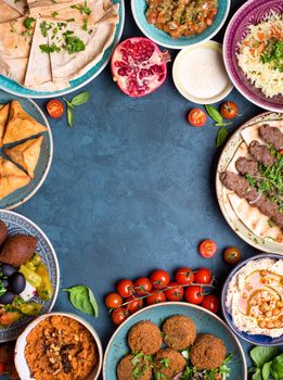 Middle eastern or arabic dishes and assorted meze on concrete rustic background. Meat kebab, falafel, baba ghanoush, hummus, sambusak, rice, tahini, kibbeh, pita. Halal food. Space for text. Top view