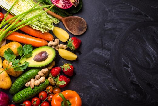 Vegetables, fruits, herbs, raw ingredients for cooking and spoon on rustic black chalk board background. Healthy, clean eating concept. Vegan or gluten free diet. Space for text. Top view. Food frame