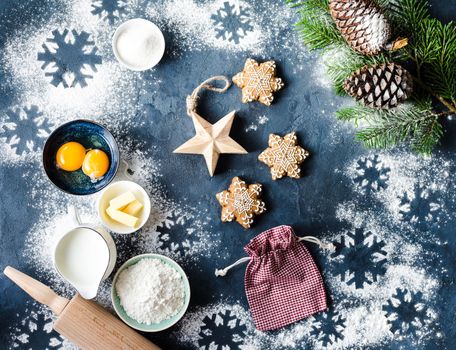 Christmas/New Year food background. Baking ingredients, snowflake cookies, Christmas decoration, gift bag. Making festive New Year sweets. Flour, rolling pin, gingerbread, milk, eggs. Top view.