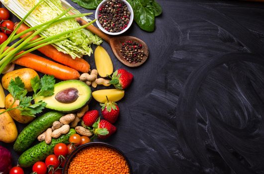 Vegetables, fruits, lentils, raw ingredients for cooking, spoon on rustic black chalk board background. Healthy, clean eating concept. Vegan or gluten free diet. Space for text. Top view. Food frame