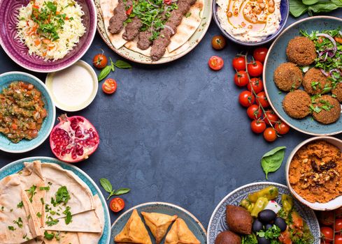 Middle eastern or arabic dishes and assorted meze on concrete rustic background. Meat kebab, falafel, baba ghanoush, hummus, sambusak, rice, tahini, kibbeh, pita. Halal food. Space for text. Top view