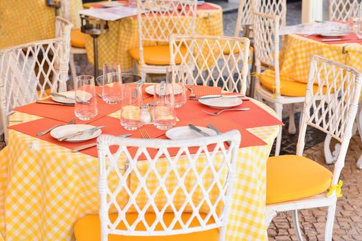 Glasses, fork, knife served for dinner in a restaurant with yellow tablecloth