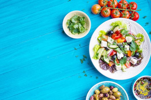 Greek salad background. Bowl with fresh greek salad, tomatoes, olives, olive oil on wooden table. Space for text. Top view. Traditional greek dish. Ingredients for making salad. Mediterranean diet