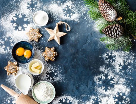 Christmas/New Year food background. Baking ingredients, snowflake cookies, Christmas decoration. Making festive New Year sweets. Flour, rolling pin, gingerbread, milk, eggs. Space for text. Top view