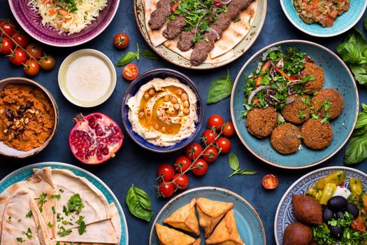 Middle eastern or arabic dishes and assorted meze, concrete rustic background. Meat kebab, falafel, baba ghanoush, muhammara, hummus, sambusak, rice, tahini, kibbeh, pita. Halal food. Lebanese cuisine