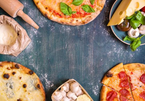 Pizza with assorted toppings and ingredients background. Space for text. Pizza, flour, cheese, tomatoes, basil, pepperoni, mushrooms and rolling pin over old wooden background. Top view. Food frame