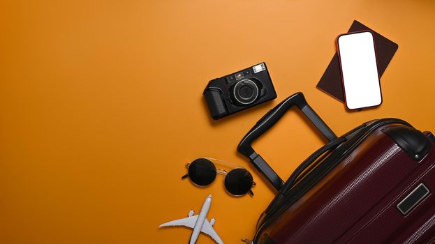 Suitcase, smart phone, sunglasses, camera and passport on yellow background for summer holidays. Top view.