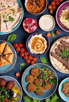 Middle eastern or arabic dishes and assorted meze, concrete rustic background. Meat kebab, falafel, baba ghanoush, muhammara, hummus, sambusak, rice, tahini, kibbeh, pita. Halal food. Lebanese cuisine