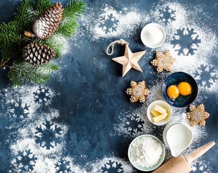 Christmas/New Year food background. Baking ingredients, snowflake cookies, Christmas decoration. Making festive New Year sweets. Flour, rolling pin, gingerbread, milk, eggs. Space for text. Top view