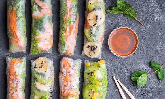 Fresh assorted spring rolls set. Handmade asian/Chinese spring rolls. Rustic concrete background. Spring rolls with shrimps, vegetables, fruits. Top view. Healthy asian food. Lunch/snacks/buffet