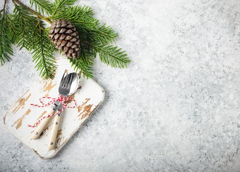 Christmas/New Year background. Christmas table place setting. Festive dinner background. Spoon, fork, fir branch on white concrete background. Christmas decoration. Space for text. Top view. Holidays