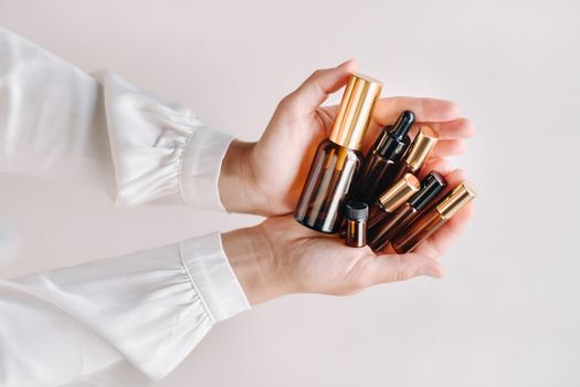 Close-up of female hands holding many bottles of essential oil. Aromatherapy.