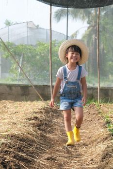 Little girl wearing a hat helps her mother in the garden, a little gardener. Cute girl playing in the vegetable garden.