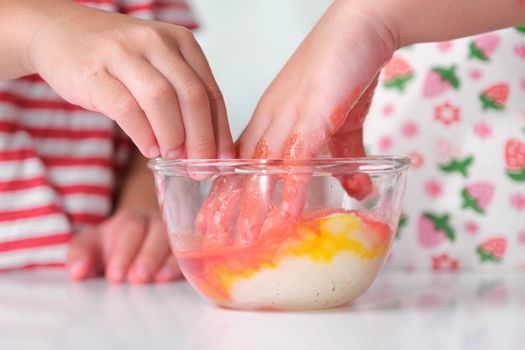 Children add food coloring to the salt in a glass bowl and mix it with their hands. Colored salt art. DIY Play and Learn Activities for Kids.