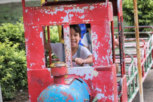 Cute little girl having fun in the outdoor playground. Young Asian sisters play together at school or kindergarten. Healthy summer activity for children.