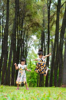 Happy children playing on the green grass in the spring garden. Two little sisters are running on a meadow in a summer park.