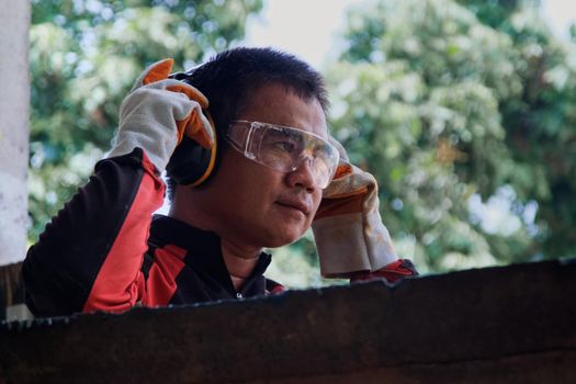 Skillful metal worker is wearing safety equipment to prepare before working at home workshop.