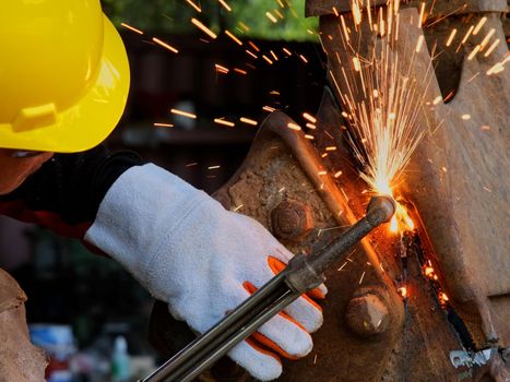 Worker cutting steel with a gas torch. Man cutting steel with propane and oxygen. Processes that use fuel gases and oxygen to weld and cut metals.