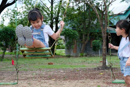 Cute little girl having fun in the outdoor playground. Young Asian sisters play together at school or kindergarten. Healthy summer activity for children.