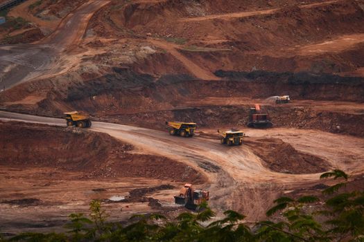 View of Trucks and excavators work in open pits in lignite coal mines. Lignite Coal Extraction Industry. The famous outdoor learning center of Mae Moh Mine Park, Lampang, Thailand.