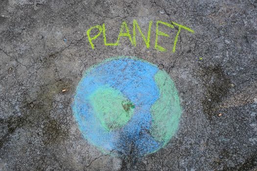 Beautiful world drawing with chalk with Planet text on asphalt. Concepts of world environment day and peace day.