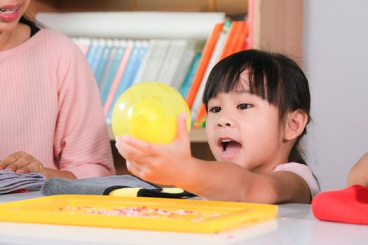 Little girl is learning and doing electrostatic science experiments with balloons in the classroom. Easy and fun science experiments for kids at home.