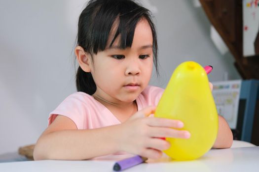 Little girl is learning and doing electrostatic science experiments with balloons in the classroom. Easy and fun science experiments for kids at home.