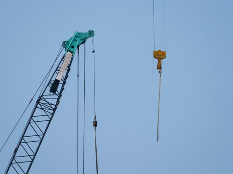 Tower cranes working on a construction site lifts a load at high-rise building in summer day. A large construction site with busy cranes.