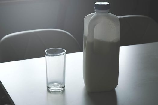 A bottle of milk and empty glass on a table in kitchen room. vintage style tone photo