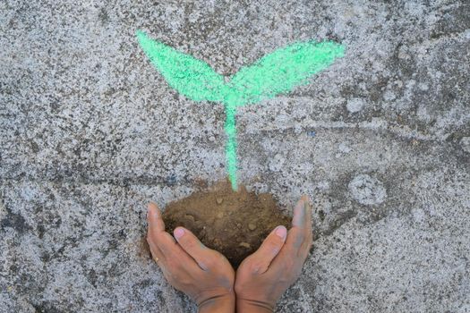 Young woman gesturing holding a drawing of a small tree on the ground in their hands. Concept of world environment day.