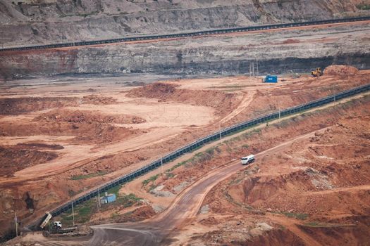 View of Trucks and excavators work in open pits in lignite coal mines. Lignite Coal Extraction Industry. The famous outdoor learning center of Mae Moh Mine Park, Lampang, Thailand.