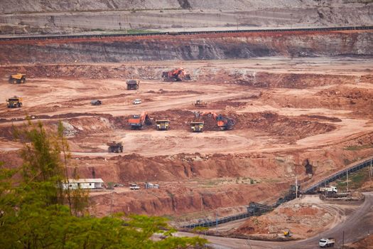 View of Trucks and excavators work in open pits in lignite coal mines. Lignite Coal Extraction Industry. The famous outdoor learning center of Mae Moh Mine Park, Lampang, Thailand.