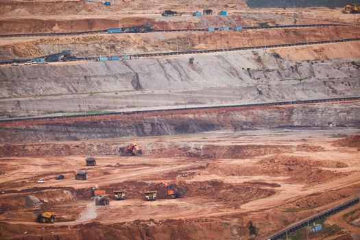 View of Trucks and excavators work in open pits in lignite coal mines. Lignite Coal Extraction Industry. The famous outdoor learning center of Mae Moh Mine Park, Lampang, Thailand.