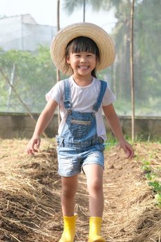 Little girl wearing a hat helps her mother in the garden, a little gardener. Cute girl playing in the vegetable garden.