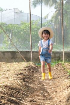 Little girl wearing a hat helps her mother in the garden, a little gardener. Cute girl playing in the vegetable garden.
