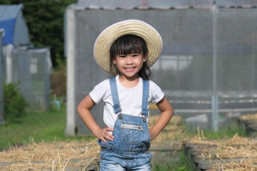 Little girl wearing a hat helps her mother in the garden, a little gardener. Cute girl playing in the vegetable garden.