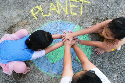 Volunteer family paints a beautiful world with the message Planet on asphalt and put hands together. Concepts of world environment day and peace day.