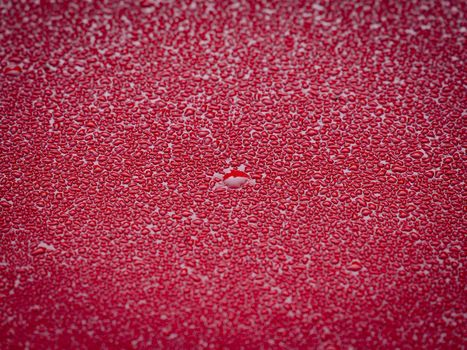 Drops of water on the hood of a red car after the rain. Close-up of water droplets on the car.