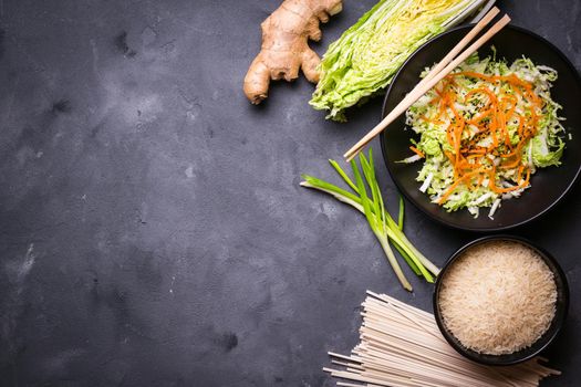 Ingredients for making chinese dinner: wheat noodles, rice, napa cabbage, ginger, green onion. Asian cooking ingredients. Top view. Preparing healthy asian meal with vegetable salad. Space for text