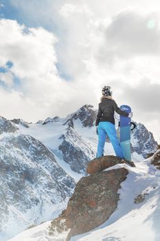 Snowboarder woman on top of rock in snowy mountain. Copy space