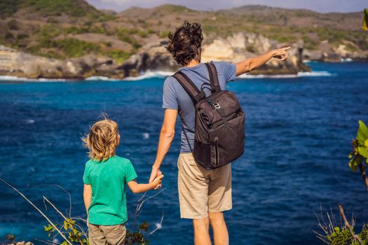 Dad and son tourists against the background of the sea Angel's Billabong in Nusa Penida, Bali, Indonesia. Travel to Bali with kids concept.