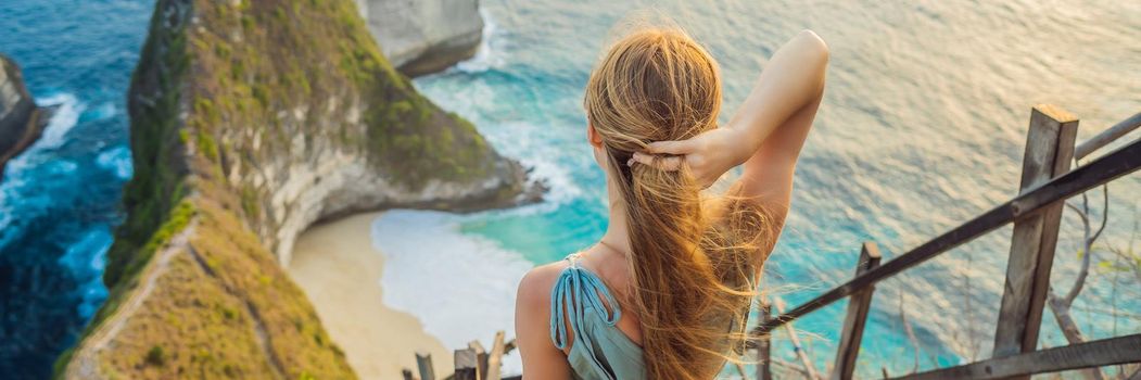 Family vacation lifestyle. Happy woman stand at viewpoint. Look at beautiful beach under high cliff. Travel destination in Bali. Popular place to visit on Nusa Penida island. BANNER, LONG FORMAT